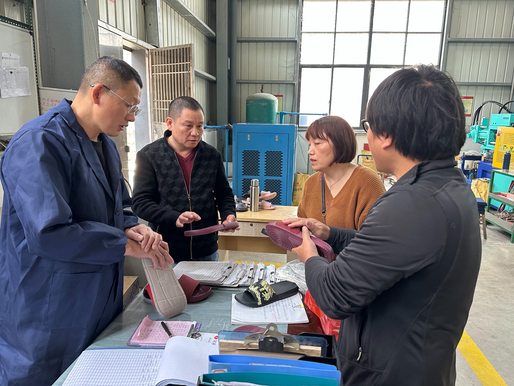Four ROWOO footwear team members discussing shoe soles in a factory workshop